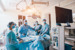 Process of gynecological surgery operation using laparoscopic equipment. Group of surgeons in operating room with surgery equipment. Background